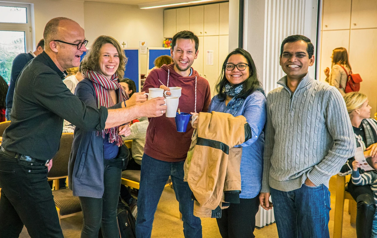 Pastor Edgar with two couples sharing coffee.