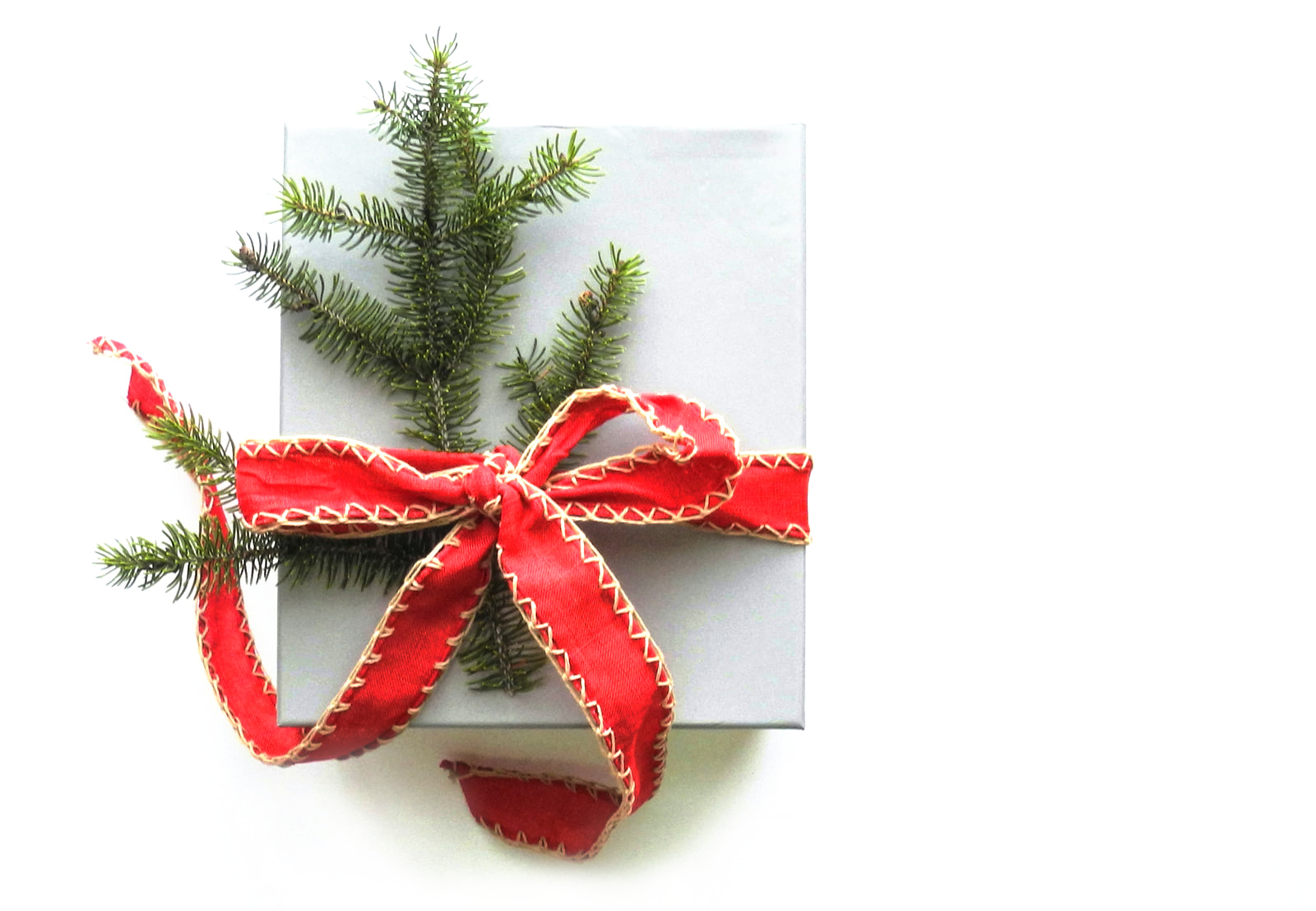 White present with red bow and pine tree branch.
